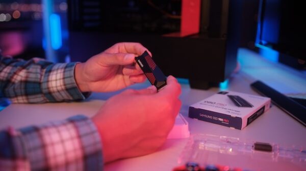 Homem segurando uma placa de armazenamento SSD sob uma luz avermelhada.